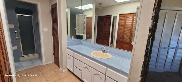 bathroom featuring vanity, a skylight, tile patterned floors, and an enclosed shower