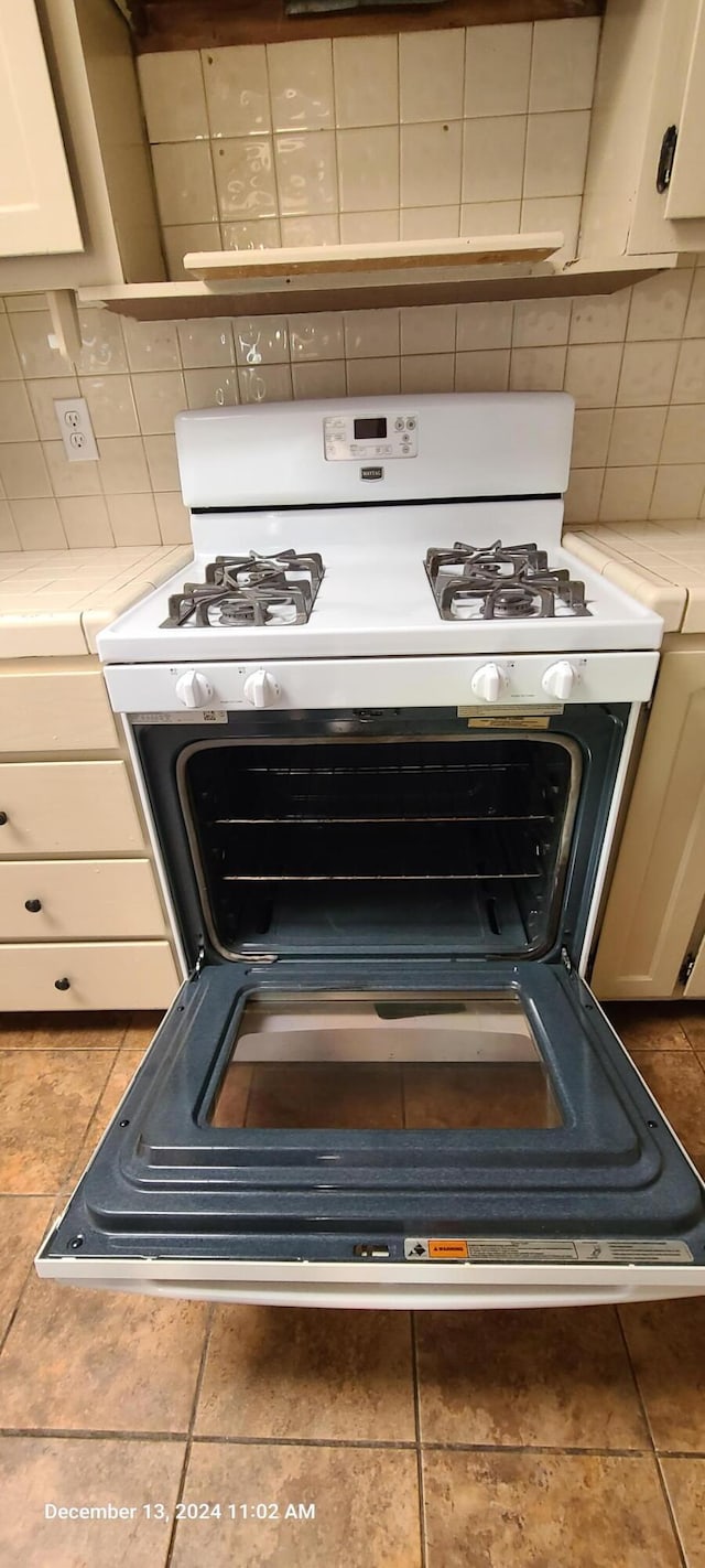 interior details featuring decorative backsplash and white range with gas stovetop