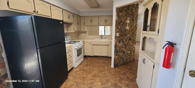 kitchen featuring sink, backsplash, cream cabinets, black refrigerator, and white gas range oven