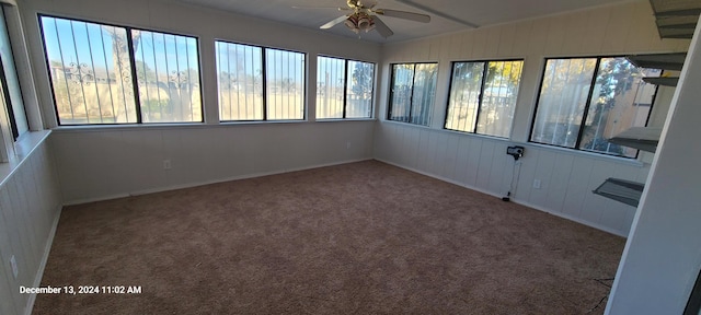 unfurnished sunroom featuring ceiling fan and a healthy amount of sunlight