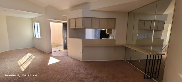 kitchen with kitchen peninsula, black refrigerator, backsplash, light colored carpet, and vaulted ceiling