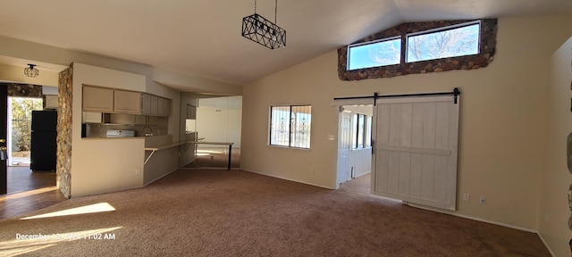 kitchen with a barn door, black fridge, plenty of natural light, and lofted ceiling