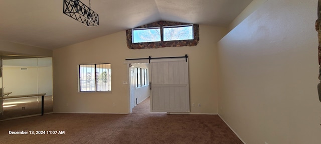 interior space with a barn door, vaulted ceiling, and plenty of natural light