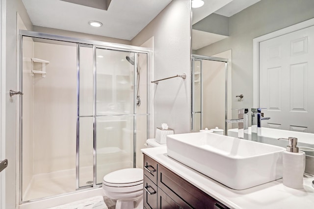 bathroom featuring vanity, a shower with shower door, and toilet