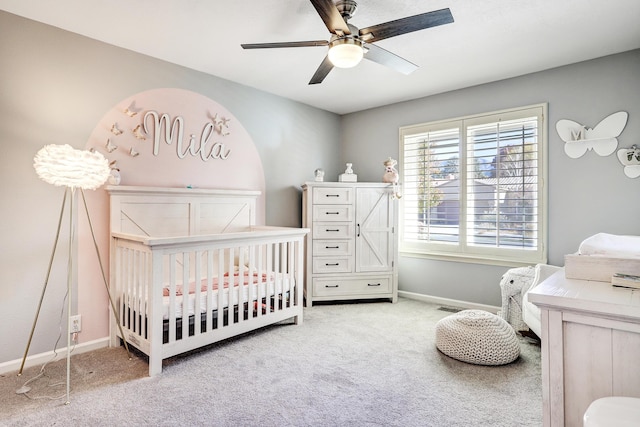 carpeted bedroom featuring a crib and ceiling fan