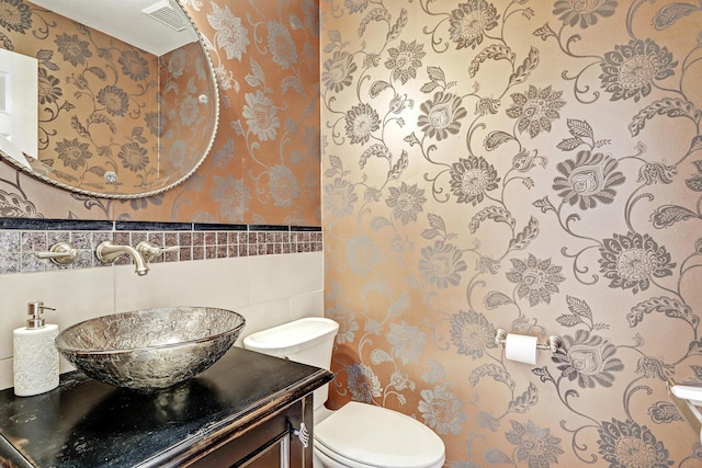 bathroom featuring vanity, tile walls, and toilet