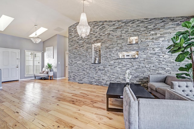 unfurnished living room featuring wood-type flooring, an inviting chandelier, and vaulted ceiling with skylight