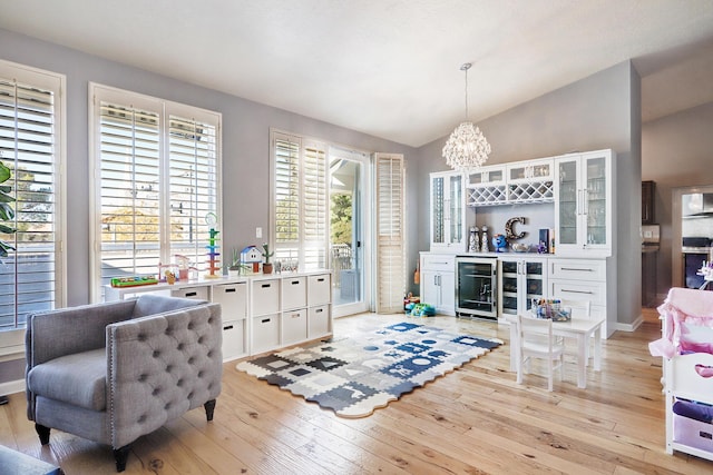 sitting room with light wood-type flooring, wine cooler, plenty of natural light, and lofted ceiling