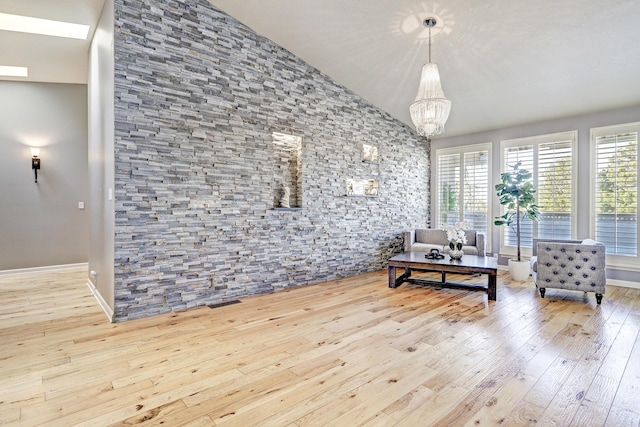 living room featuring an inviting chandelier, lofted ceiling, and light hardwood / wood-style flooring