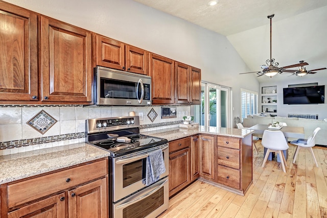 kitchen with light stone countertops, hanging light fixtures, light hardwood / wood-style flooring, kitchen peninsula, and appliances with stainless steel finishes