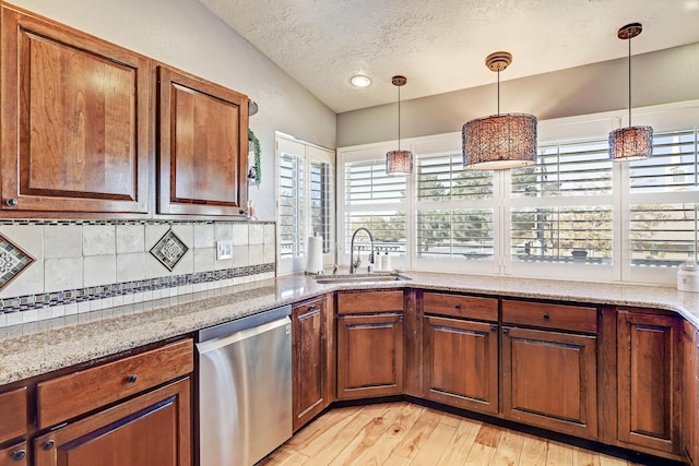 kitchen with dishwasher, sink, light stone countertops, light wood-type flooring, and tasteful backsplash