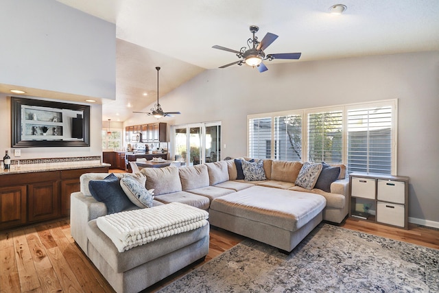 living room with ceiling fan, high vaulted ceiling, and light hardwood / wood-style floors