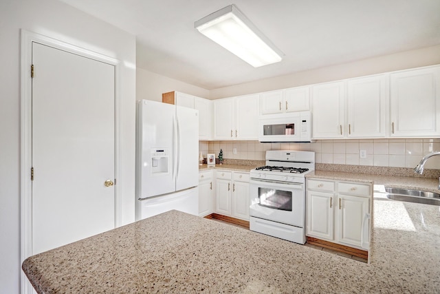 kitchen featuring white appliances, sink, tasteful backsplash, light stone counters, and white cabinetry