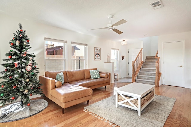 living room with a textured ceiling, light hardwood / wood-style flooring, and ceiling fan