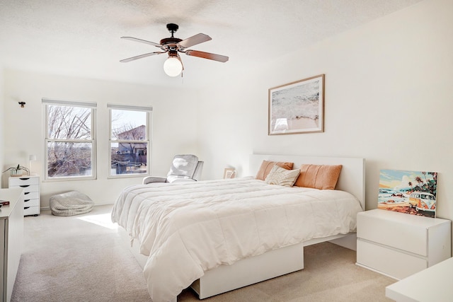 carpeted bedroom featuring ceiling fan and a textured ceiling