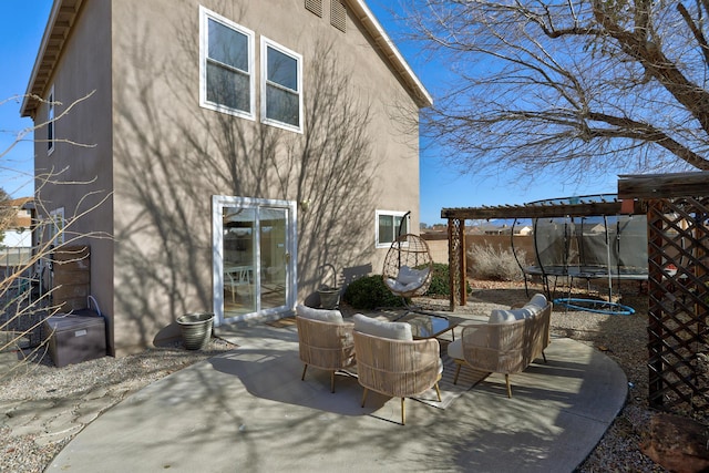 rear view of property featuring a pergola, a trampoline, and a patio