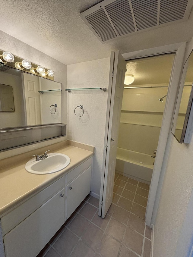 bathroom featuring tile patterned flooring, vanity, shower / tub combination, and a textured ceiling