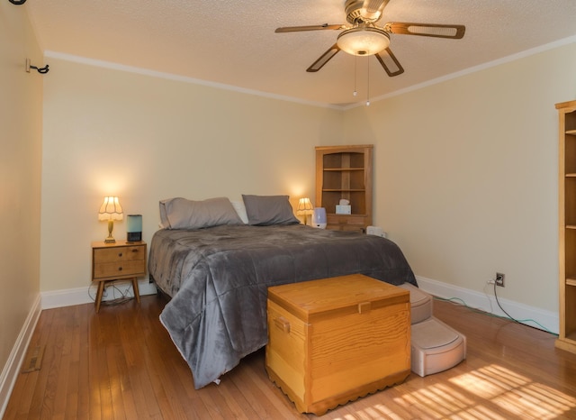 bedroom featuring ceiling fan, wood-type flooring, a textured ceiling, and ornamental molding