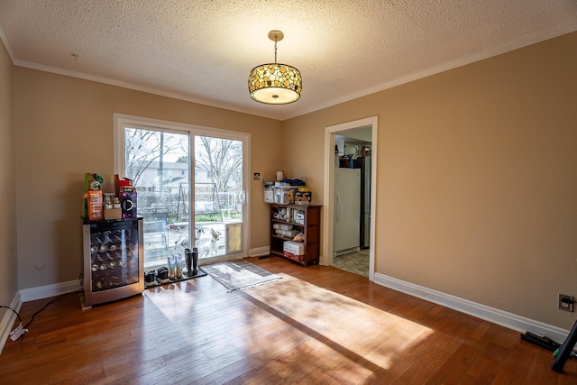 interior space with crown molding, beverage cooler, a textured ceiling, and hardwood / wood-style flooring