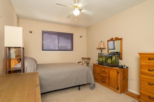 bedroom featuring ceiling fan, a textured ceiling, and light carpet