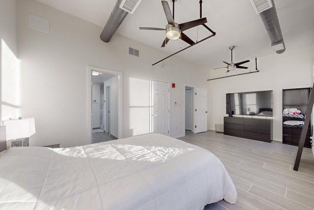 bedroom featuring ceiling fan, light hardwood / wood-style floors, and a high ceiling