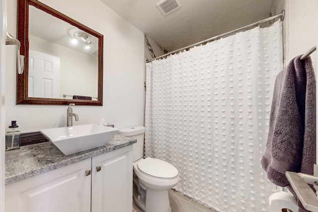 bathroom featuring tile patterned floors, vanity, toilet, and a textured ceiling