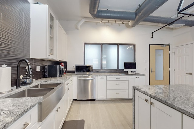 kitchen with light stone countertops, white cabinetry, and stainless steel appliances