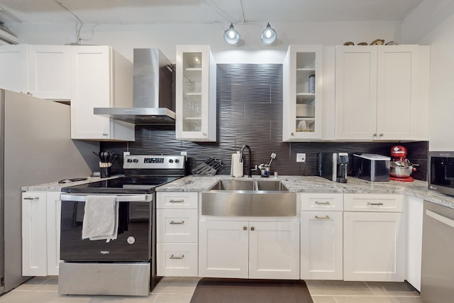 kitchen featuring sink, wall chimney exhaust hood, stainless steel appliances, white cabinets, and light tile patterned flooring