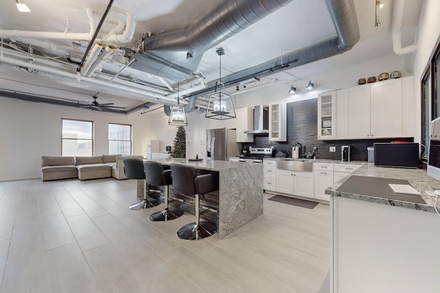 kitchen featuring white cabinets, sink, wall chimney exhaust hood, stainless steel fridge, and tasteful backsplash