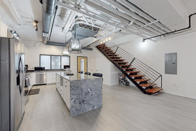 kitchen featuring electric panel, a center island, white cabinets, and appliances with stainless steel finishes