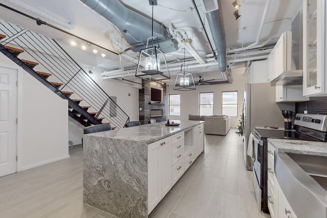 kitchen with white cabinetry, a large fireplace, electric range, and light stone counters