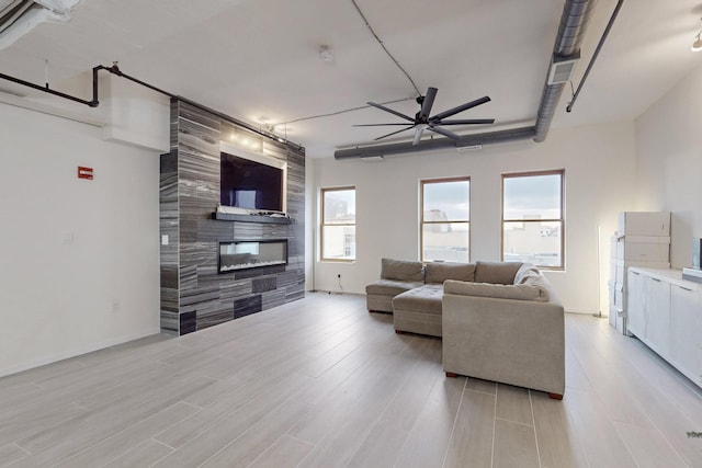 living room featuring a tile fireplace, ceiling fan, and light hardwood / wood-style floors