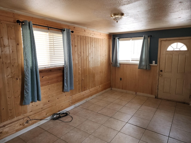 foyer entrance with wooden walls, plenty of natural light, and a textured ceiling