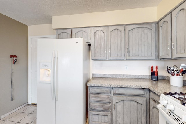 kitchen featuring gray cabinetry, white appliances, a textured ceiling, and light tile patterned flooring