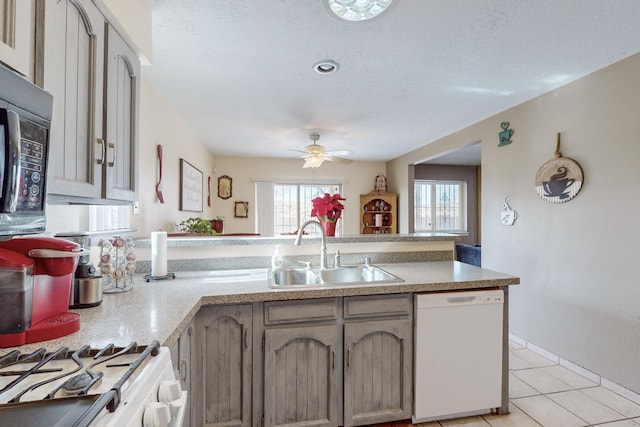 kitchen featuring light tile patterned flooring, sink, white appliances, ceiling fan, and a textured ceiling