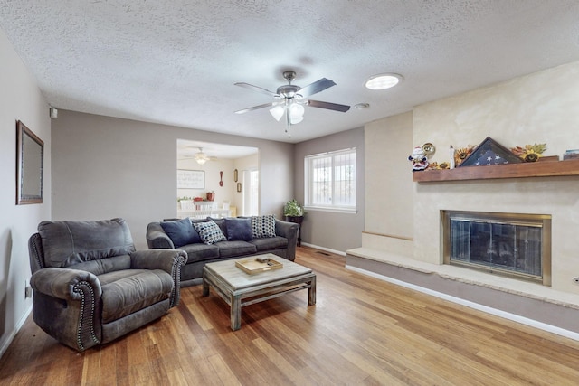 living room with ceiling fan, light hardwood / wood-style floors, and a textured ceiling