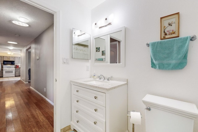 bathroom with hardwood / wood-style flooring, vanity, a textured ceiling, and toilet