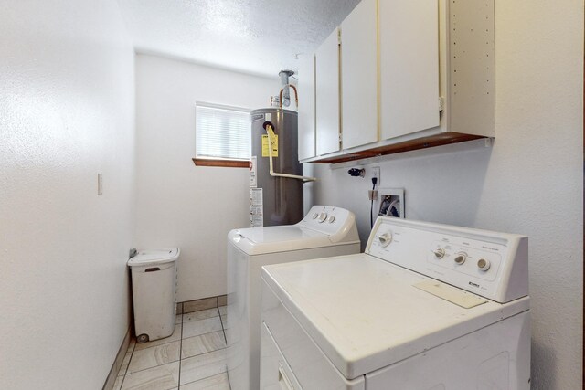 laundry area with cabinets, washing machine and clothes dryer, a textured ceiling, and gas water heater