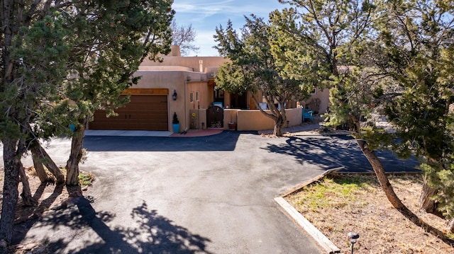 2 Chaco Ct, Sandia Park, NM 87047 - pueblo-style house with asphalt driveway, a garage, and stucco siding