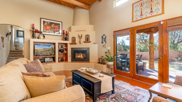 2 Chaco Ct, Sandia Park, NM 87047 - living room featuring a fireplace, healthy amount of natural light, a towering ceiling, french doors, and a wooden ceiling with exposed beams