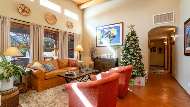 living room with beamed ceiling and a towering ceiling