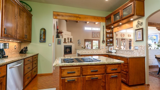 kitchen with kitchen peninsula, tasteful backsplash, light stone counters, stainless steel appliances, and a center island