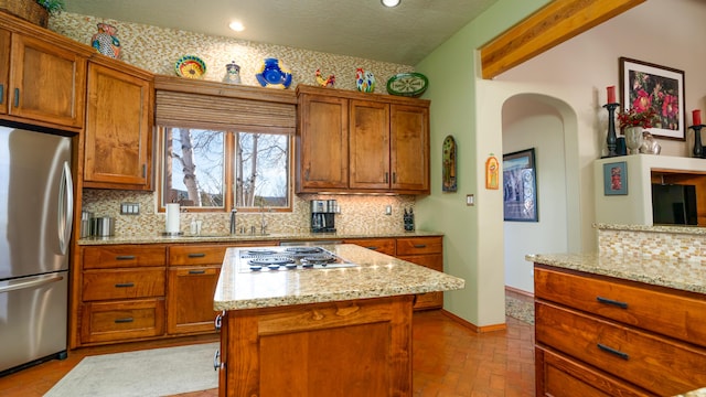 2 Chaco Ct, Sandia Park, NM 87047 - kitchen with freestanding refrigerator, backsplash, brown cabinets, recessed lighting, and a textured ceiling