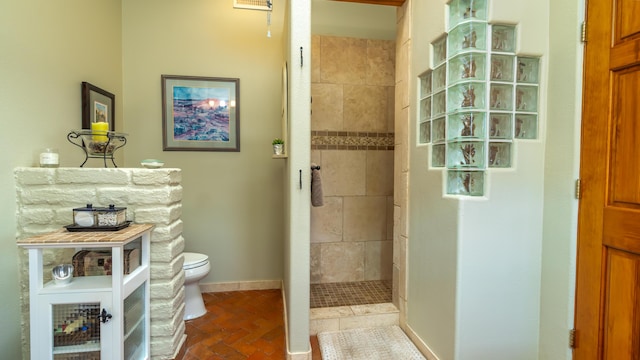 bathroom featuring toilet and a tile shower