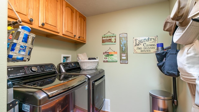 clothes washing area with cabinets and independent washer and dryer