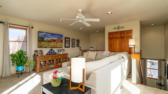 living room featuring ceiling fan, light colored carpet, and a textured ceiling