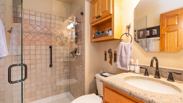 bathroom with vanity, toilet, and a shower with door