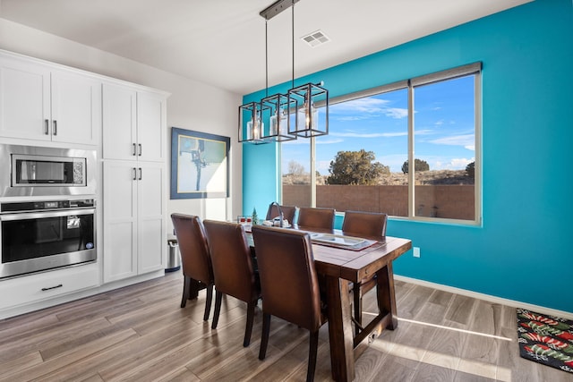 dining room featuring baseboards, an inviting chandelier, visible vents, and light wood-style floors