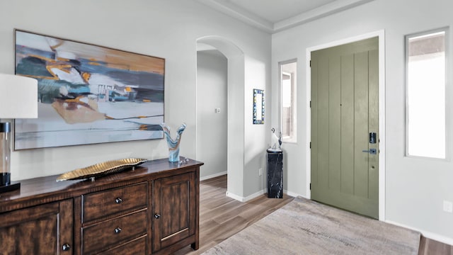 foyer entrance with arched walkways, wood finished floors, and baseboards