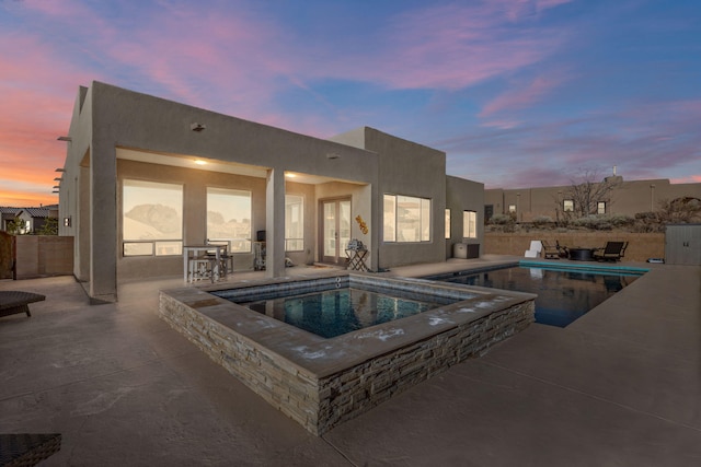 pool at dusk featuring an in ground hot tub, a patio, and a fenced in pool